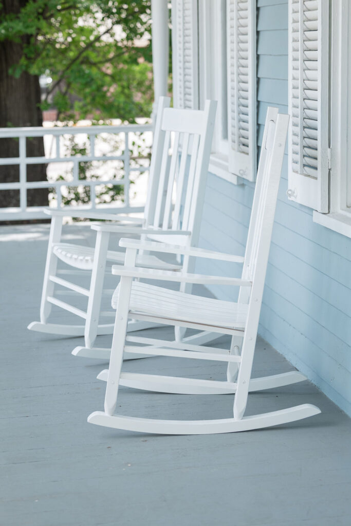 Empty white rocking chairs on the front porch of the Heritage Brands office in Columbia, South Carolina.