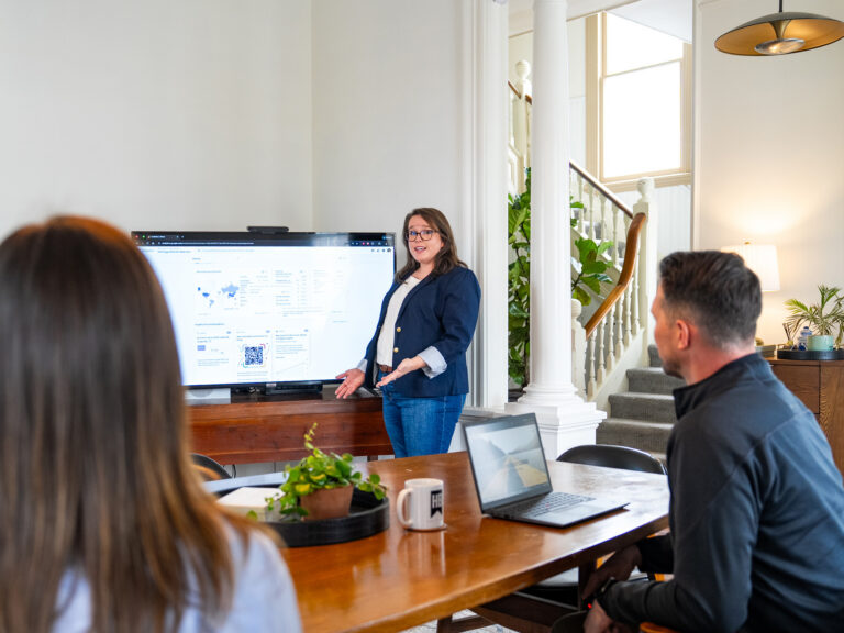 Senior marketing strategist presenting campaign performance data to colleagues during a strategy meeting at Heritage Brands.